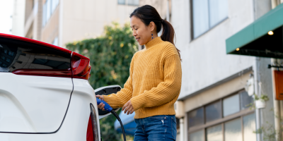 Woman charging electric vehicle on public street