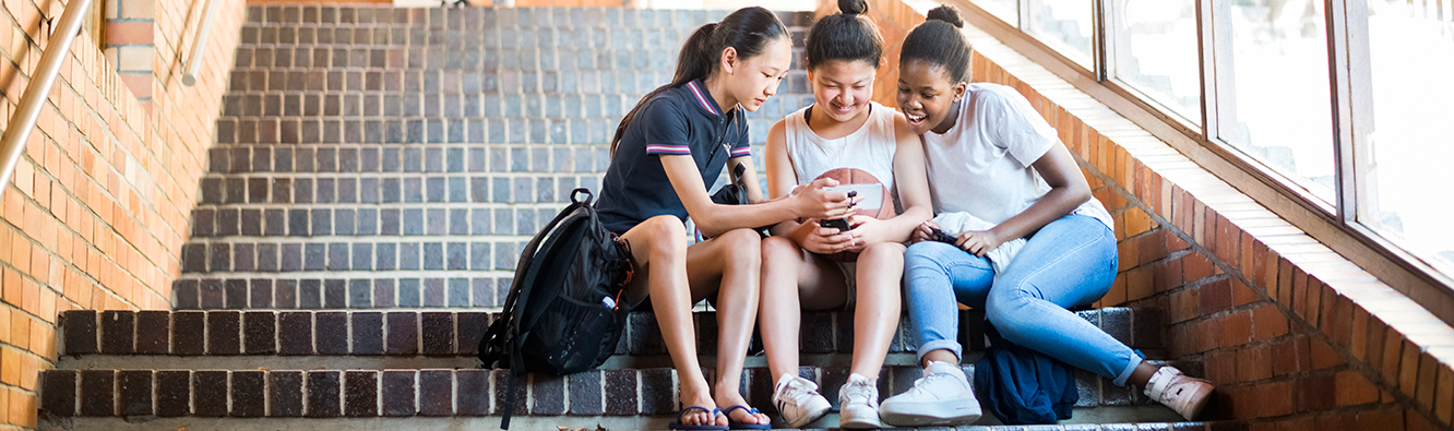 Three teens sitting on stairs looking at phone