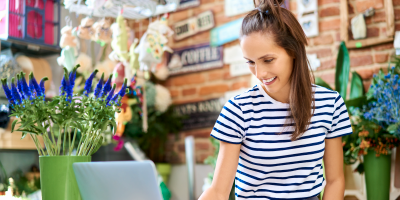 Woman in flower shop using laptop, florist