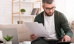 Man with papers typing on calculator