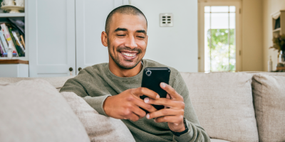 Man checking his phone on the couch at home