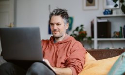 Man sitting on couch using laptop.