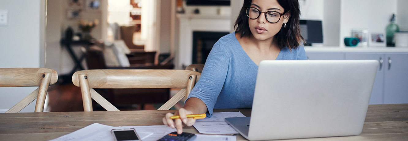 woman looking at computer taking notes