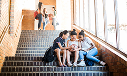 teenagers sitting on stairs looking at a mobile device