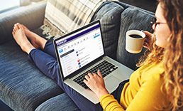 Woman with coffee mug sitting on couch with her laptop open to the Pioneer website