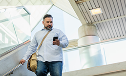 man walking down stairs and looking at a mobile device