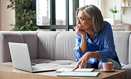 Person sitting at coffee table with papers and a laptop