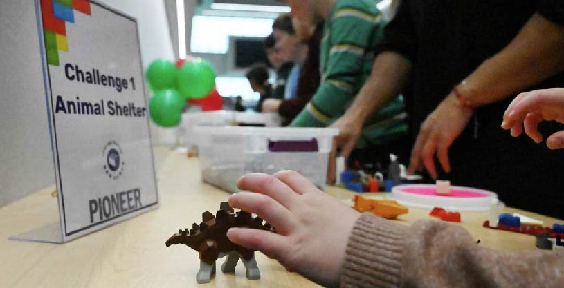 Child working on Legos at a workstation that says: Challenge 1 Animal Shelter