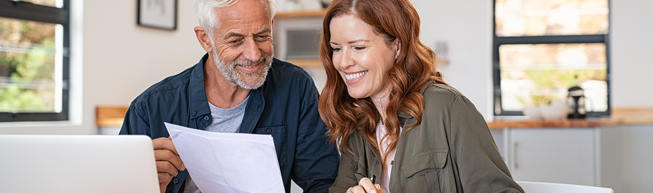 man and woman looking at paperwork and computer