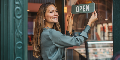 Woman small business owner turning open sign on door