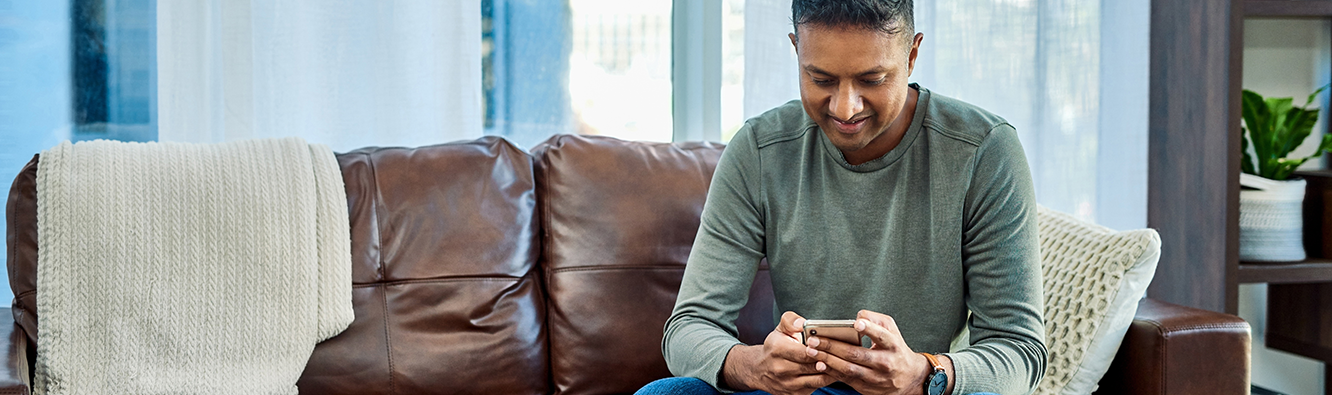 man sitting on a couch looking at a mobile device