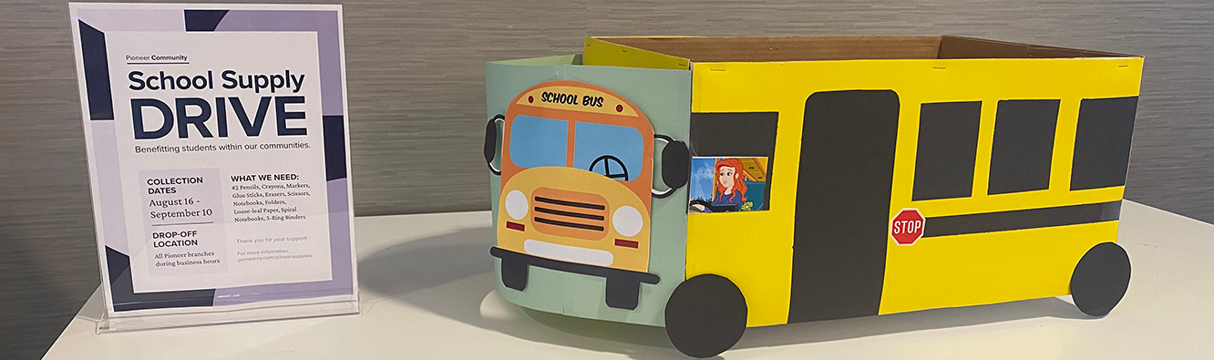 School Supply Drive flyer and paper school bus on a table