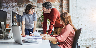 people meeting at a table with computers