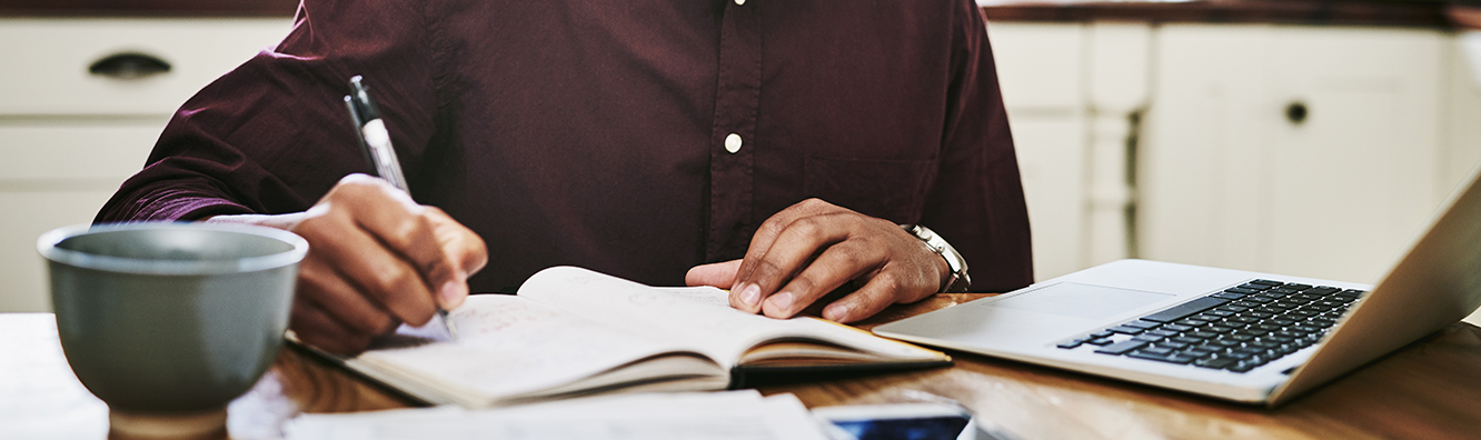 person looking at a laptop and taking notes