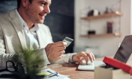 Person holding credit card while shopping online on laptop