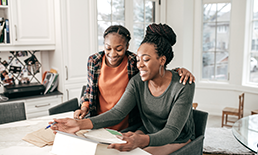 teen and mom looking at papers and tablet screen