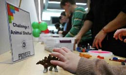 Child working on Legos at a workstation that says: Challenge 1 Animal Shelter