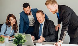 Four professionals looking at a computer screen