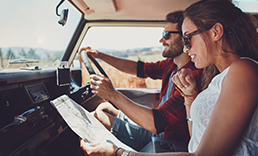Young couple on a road trip looking at a map.