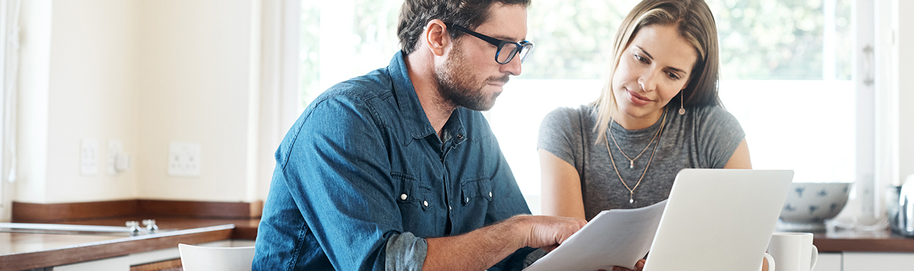 man and woman looking at paperwork and laptop