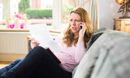 Woman on phone at home looking at paper