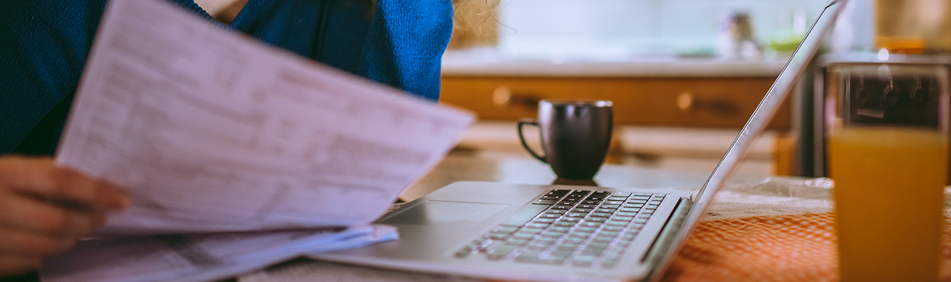 person looking at paperwork in front of a computer