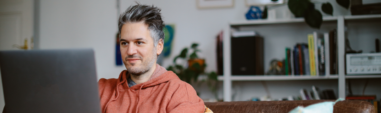 Man sitting on couch using laptop.