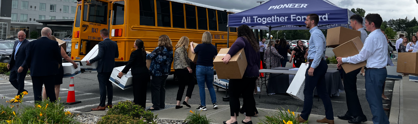 Pioneer employees lined up to load school bus with school supplies