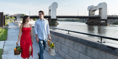 Couple walking in Troy with the Green Island Bridge in the background