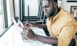 Man looking at this computer completing a checklist.