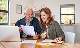 Couple looking at paperwork in front of an open laptop