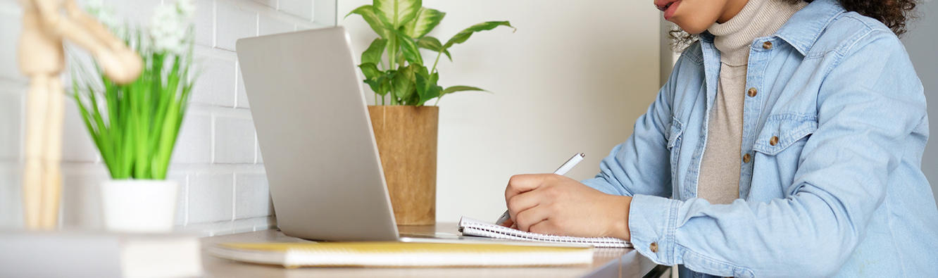 person looking at laptop and writing notes