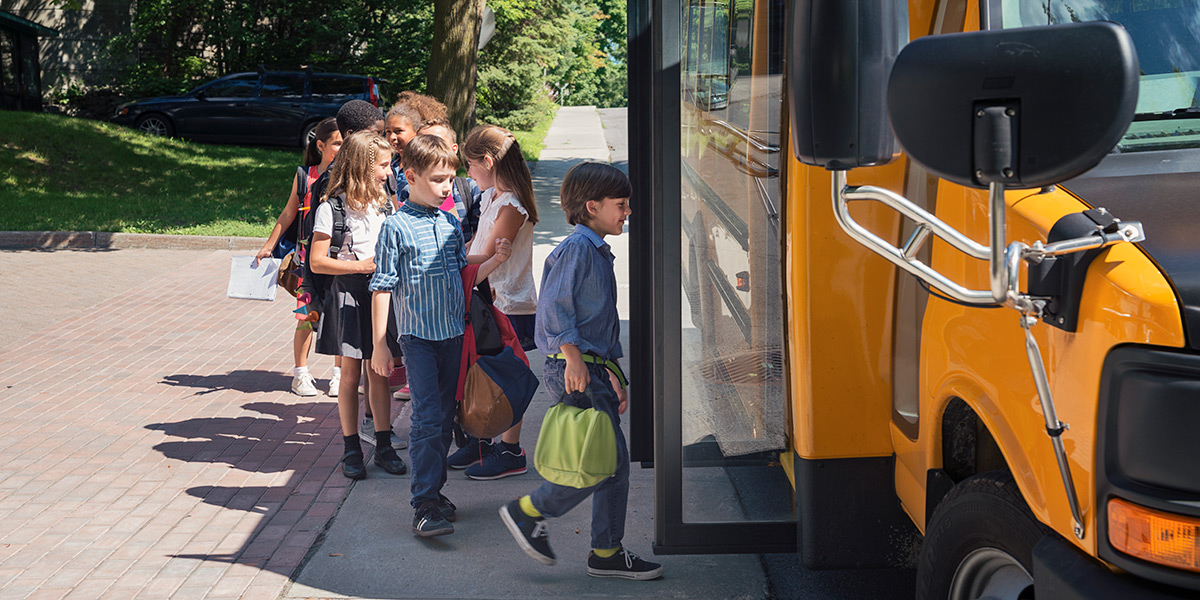 children in line to get on a school bus