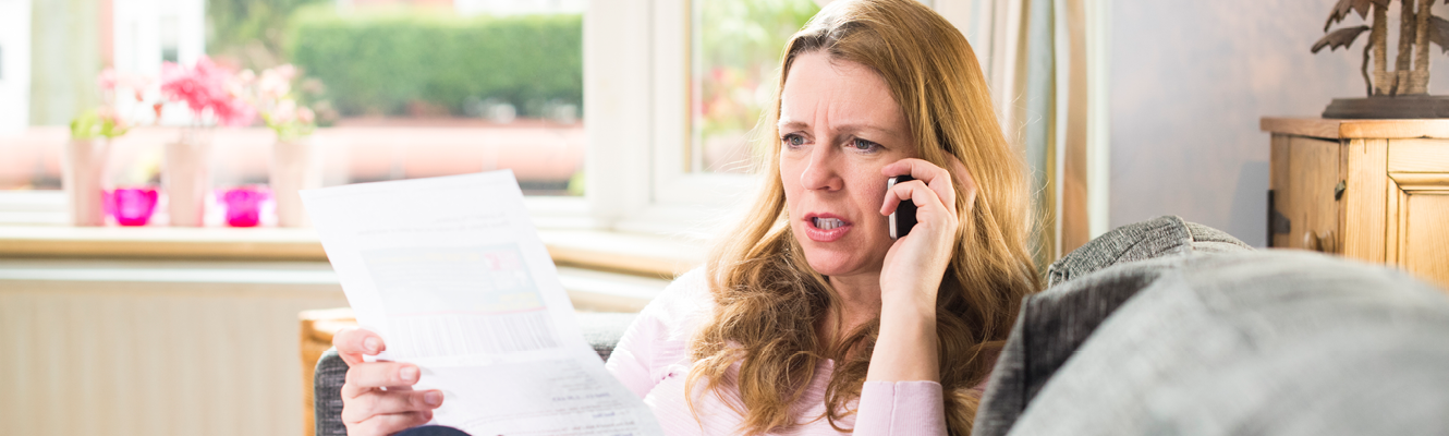 Woman on phone at home looking at paper