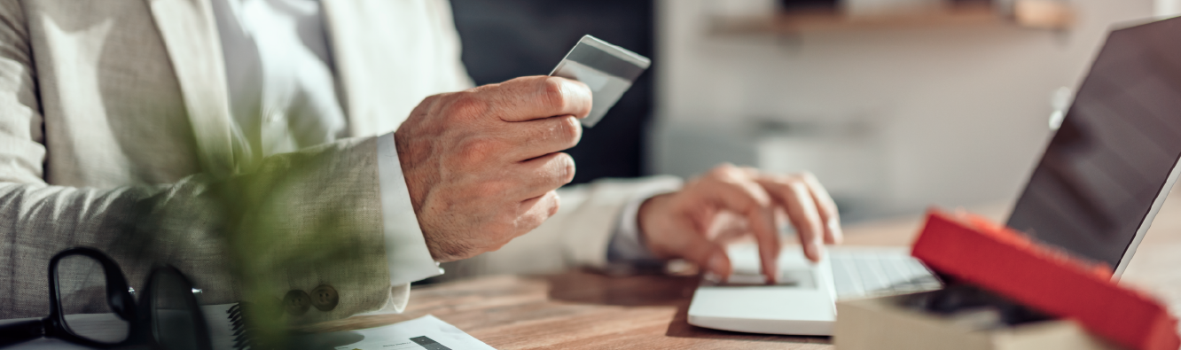 Person holding credit card while shopping online on laptop