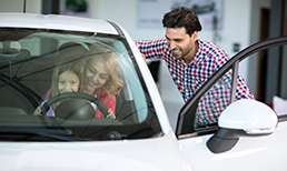 Family of three test driving a new car.