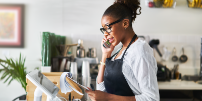 Small business owner taking a phone call while reviewing notes