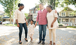 Two seniors, and adult woman and a young girl walking in a suburban neighborhood